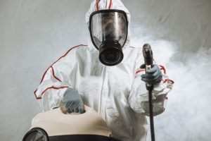 Worker in hazmat suit using fogging machine