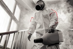 Person in hazmat suit with fogging sprayer